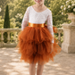 Flower girl dress in burnt orange tiered tutu style tulle with long white lace sleeves. 