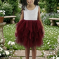 burgundy tulle flower girl dress in a tiered tutu style. Made knee length with a sleeveless white lace top. 