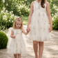 flower girl dress in white tulle with embroidered floral dress. In a sleeveless knee length style. 